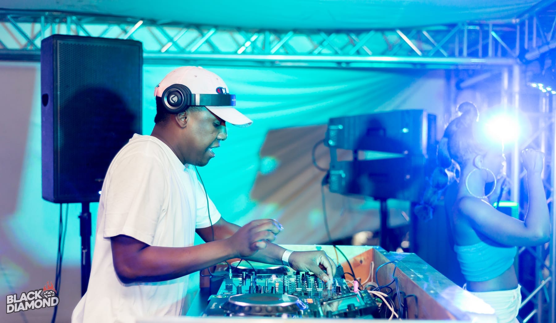 DJ in a white cap at the decks, lit blue