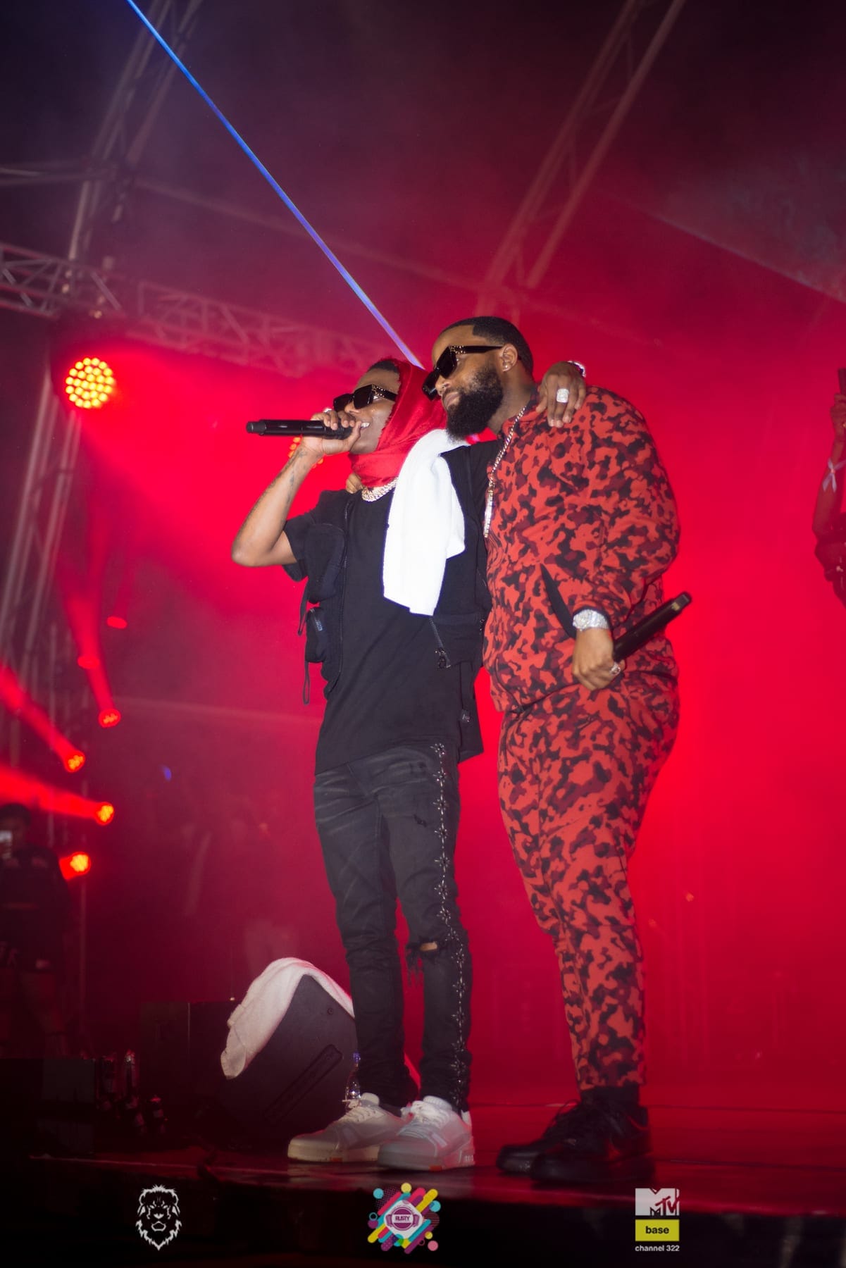 Two performers in red under the stage rig