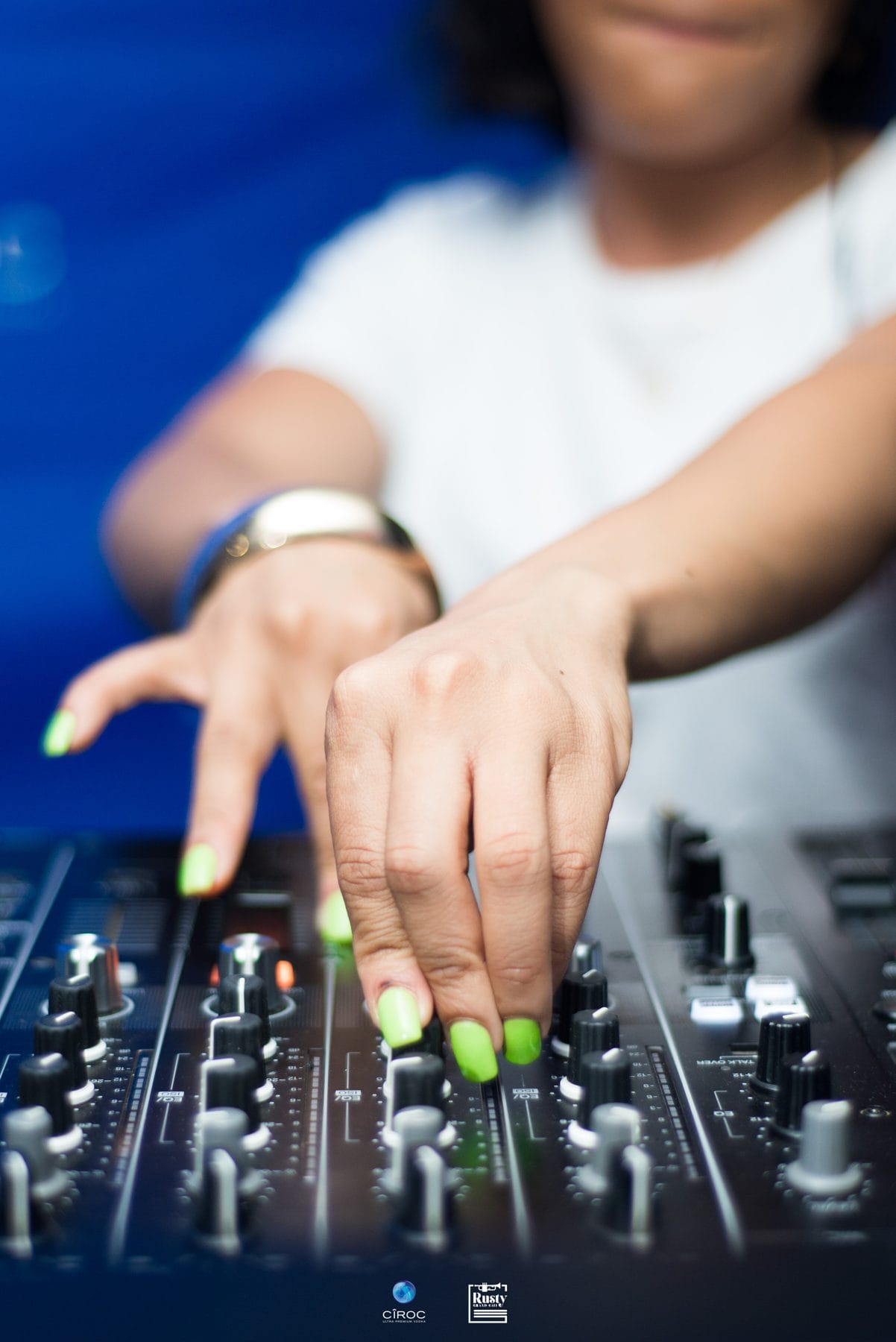 Hands with green nails on a DJ mixer