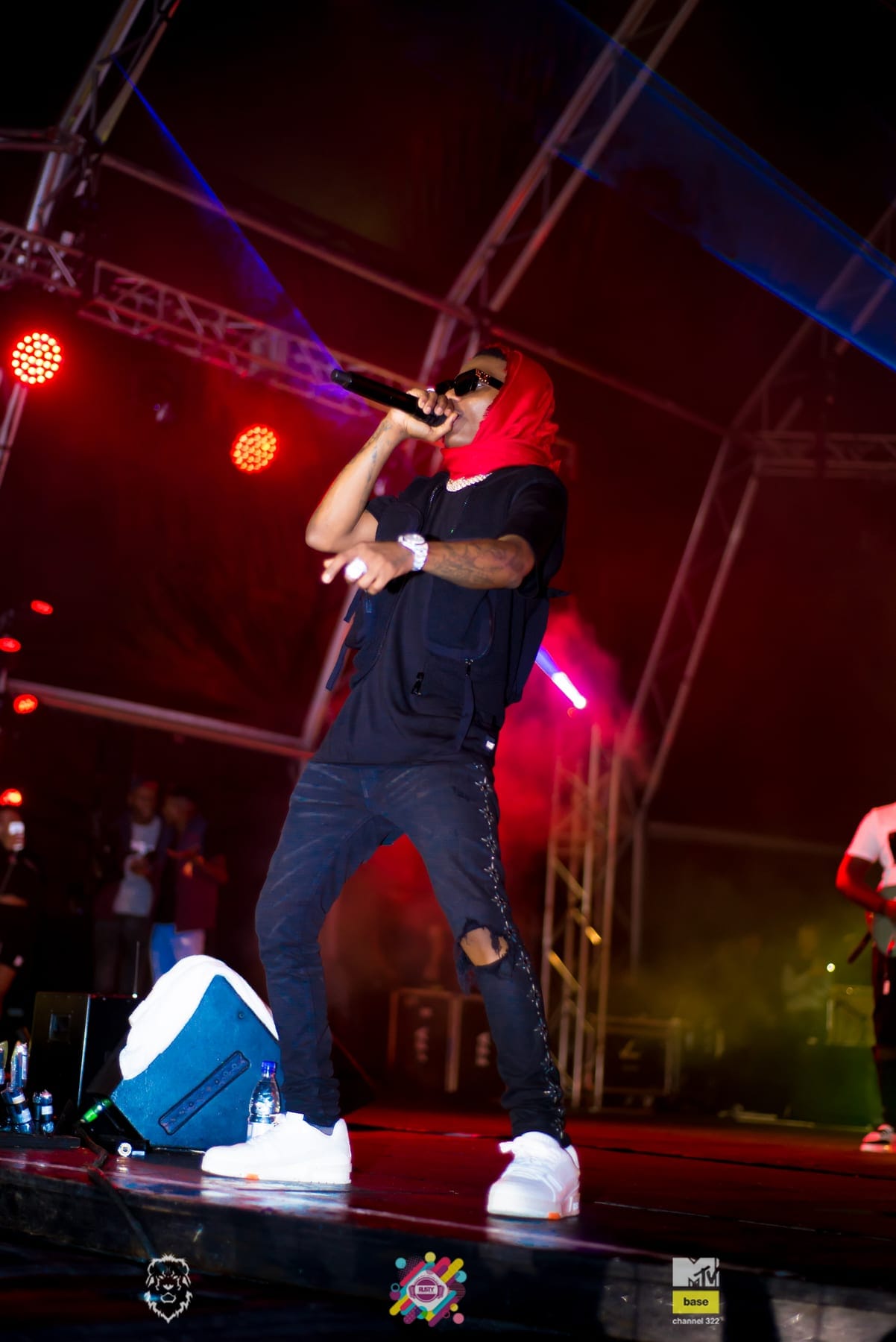 Rapper in a red cap working the mic under the rig