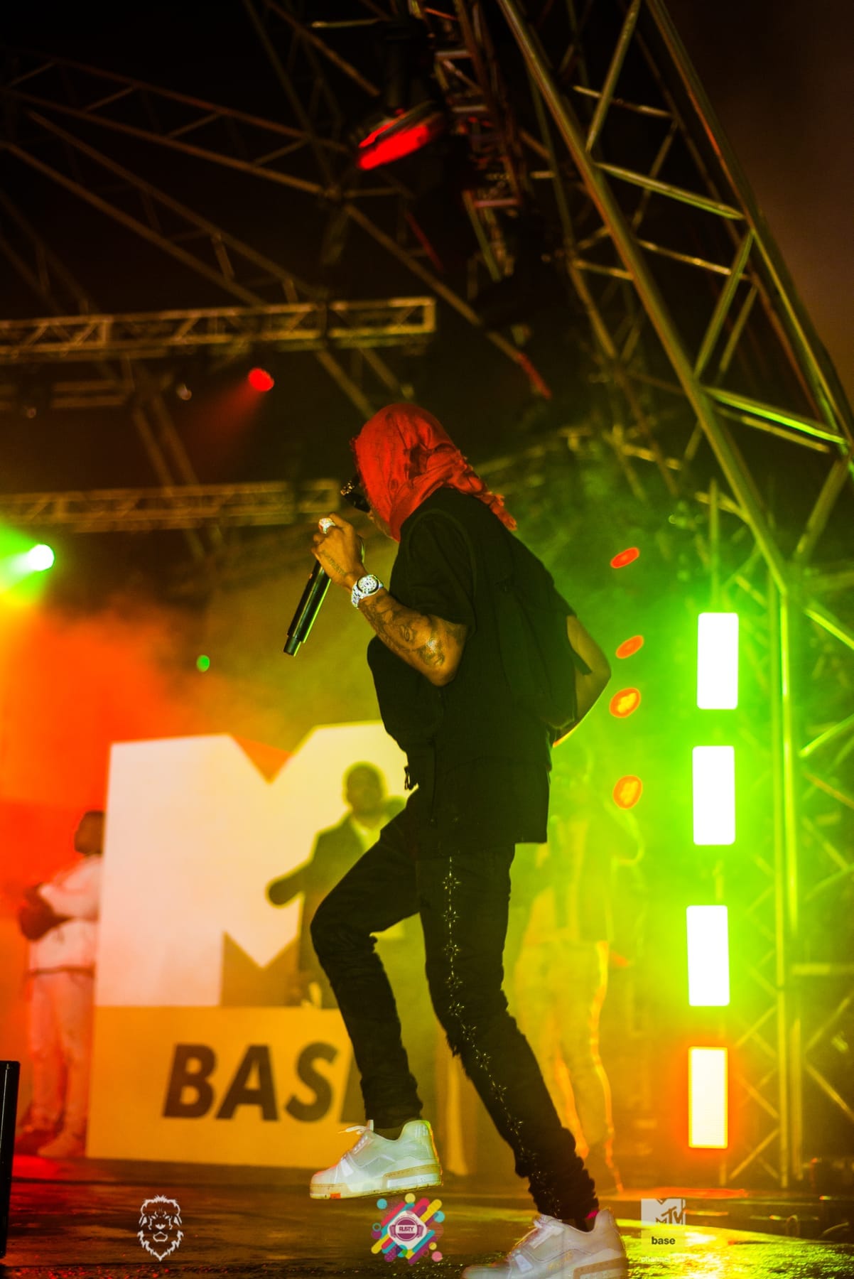 Performer in a red hood beside the MTV Base logo in green and orange light