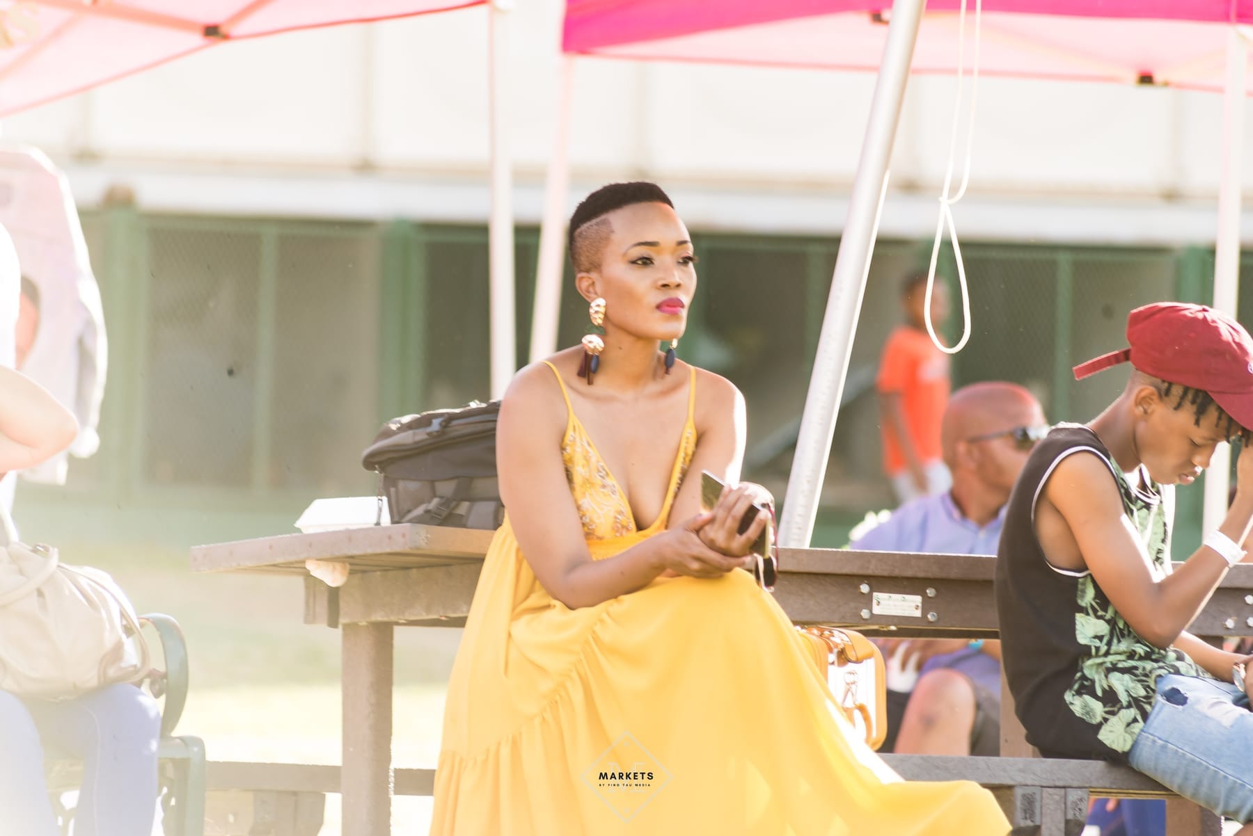 Woman in a yellow dress seated at a daytime festival