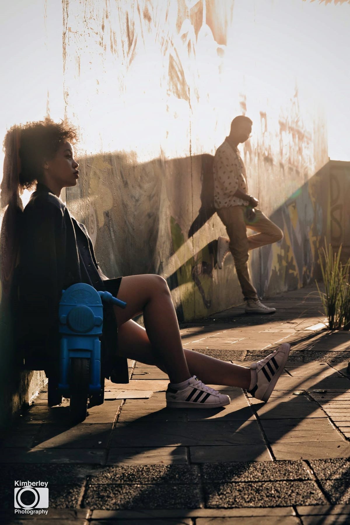 Two seated against a sunlit painted wall